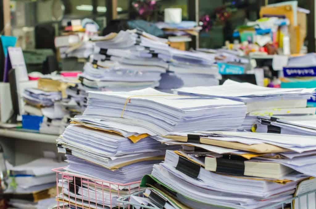 Stacks of papers and folders sit on desks, illustrating the large quantity of claims that can end in bad faith insurance.